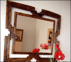 a mirror that is sitting on top of a table with red flowers in front of it