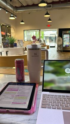 an open laptop computer sitting on top of a table next to a cup and tablet