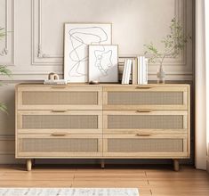 a wooden dresser sitting next to a plant and pictures on top of it in a living room