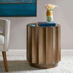 a vase with flowers sitting on top of a table next to a chair and painting