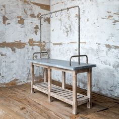 an industrial work bench in front of a wall with peeling paint and metal fittings