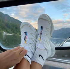 someone's feet sticking out the side of a boat window with mountains in the background