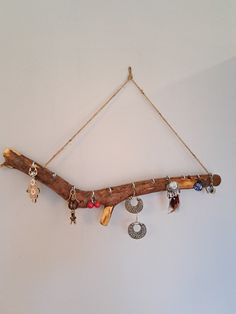 a piece of driftwood hanging on a wall with various jewelry pieces attached to it