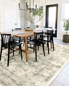 a dining room table with four chairs and a potted plant in the center on top