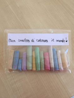 small crayons are in a clear bag on a wooden table with a note