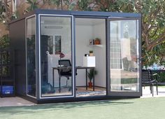 a small office in the middle of a backyard with glass walls and sliding doors on both sides