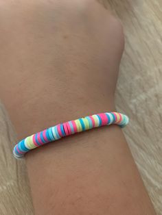 a person wearing a bracelet with multicolored stripes on it's wrist and arm