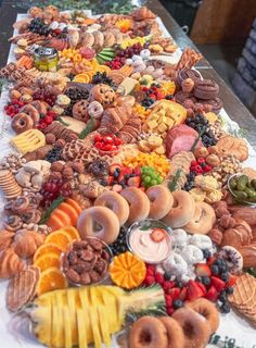 a long table covered in lots of different types of donuts and other food items