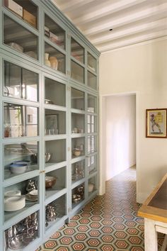 a kitchen with blue glass cabinets and patterned floor tiles on the floor, along with a wooden dining table