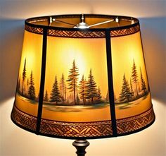 a lamp that is on top of a white wall with trees painted on the lampshade