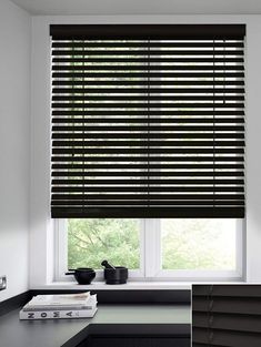 a kitchen window with black blinds in the windowsill and an empty counter top next to it