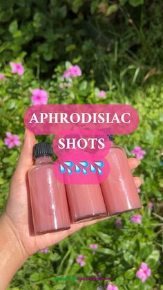 someone holding three bottles with pink liquid in front of some purple flowers and the words aphrodisic shots