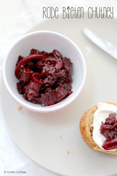 a white plate topped with a small bowl filled with cranberry sauce next to a pastry