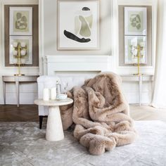 a living room with white furniture and pictures on the wall, including a fur throw blanket