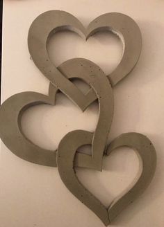 two heart shaped metal pieces sitting on top of a white table next to each other