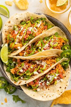 three tacos with shredded meat, lettuce and salsa in a skillet