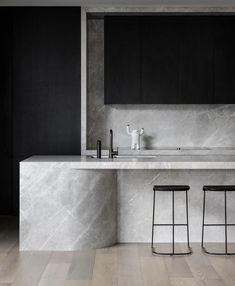 two stools are in front of a marble countertop and sink with black cabinets