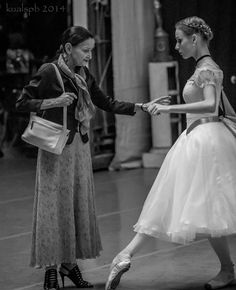 two women in dresses are dancing on the street