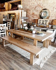 a large wooden table sitting on top of a hard wood floor next to a brick wall