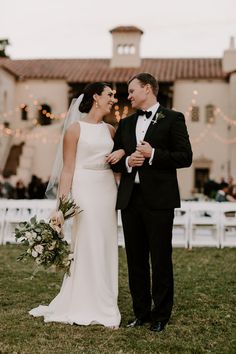 a bride and groom standing in front of a large building at their wedding ceremony,