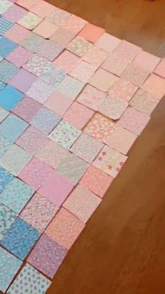 a wooden table topped with pink and blue patchwork quilts on top of it