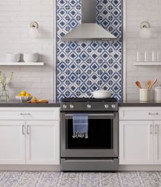 a kitchen with blue and white tiles on the wall, an oven hood and counter tops