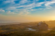 the sun is setting over an ocean and some houses