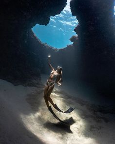 a woman is swimming in the water near rocks