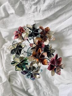 a bunch of paper flowers sitting on top of a white cloth covered bed sheet,