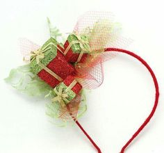 a red headband with green and gold bows on it, sitting on top of a white surface