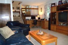 a living room filled with furniture and a flat screen tv mounted to a wall above a wooden coffee table