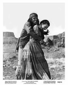 an old black and white photo of a woman holding a child in her arms with mountains in the background