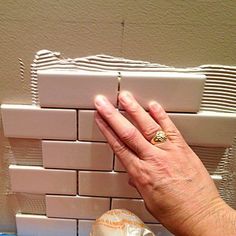 a person's hand on the wall next to a toilet paper dispenser