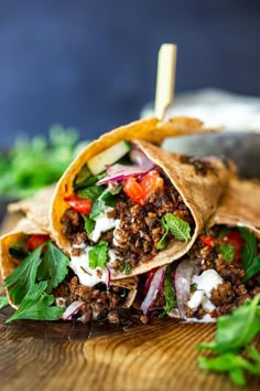 a burrito filled with meat and veggies on top of a wooden cutting board