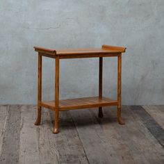 a wooden table sitting on top of a hard wood floor next to a gray wall