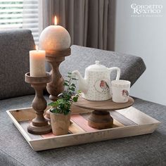 a tray that has some tea cups on it and a lit candle in the middle