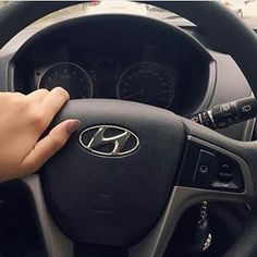 a person holding the steering wheel of a car with their hand on the steering wheel