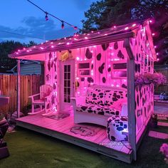 a small pink house with lights on it's roof and furniture in the yard