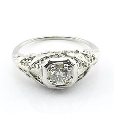 an antique diamond ring with filigrees on the sides, set in white gold