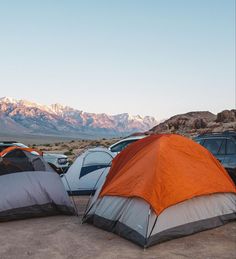 several tents set up in the desert with mountains in the background