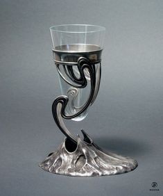 a silver goblet sitting on top of a gray table next to a wall