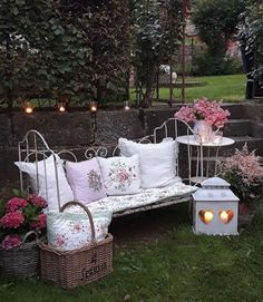 a white bench sitting in the middle of a lush green field next to flowers and candles