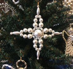 a snowflake ornament hanging from a christmas tree with ornaments around it