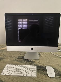 an apple desktop computer sitting on top of a desk next to a keyboard and mouse