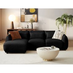 a living room with a large black couch and white rugs on the floor next to a potted plant