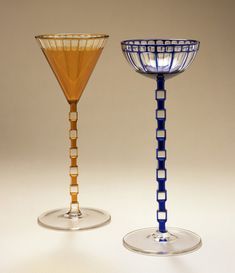 two glass goblets sitting side by side on a white surface with no one around them