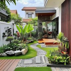 a garden with grass, rocks and plants in front of a house's entrance