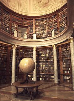 the inside of a library with many bookshelves and a large globe in the center