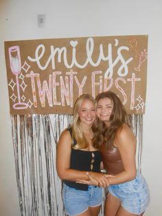 two young women standing next to each other in front of a sign