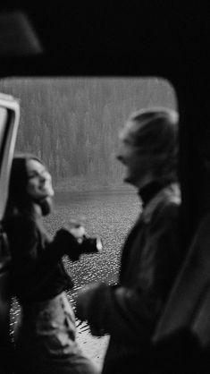 black and white photograph of two people sitting in the back of a car looking at something